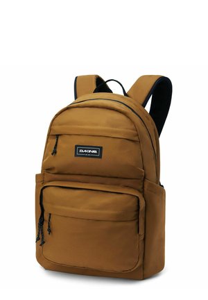 Mochila de tela marrón con correas de hombro acolchadas, un bolsillo frontal con cremallera y un parche con el logotipo de la marca en el compartimento principal.