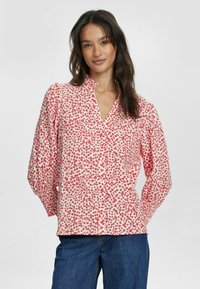 Blusa con stampa floreale rossa, collo a V e maniche lunghe a sbuffo. Realizzata in tessuto leggero con sfondo bianco e piccoli fiori sparsi.