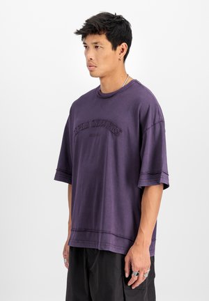 T-shirt oversize violet à manches courtes, col rond, avec un logo "Alpha Industries" brodé sur le devant. Matière en mélange de coton.