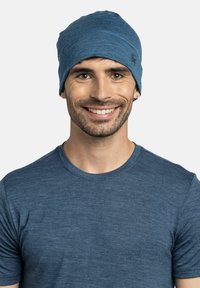 Blue beanie made of soft, textured fabric, featuring a snug fit and subtle stitching details. Worn with a matching blue T-shirt.