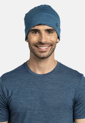 Blaues Beanie aus weichem, strukturiertem Stoff mit enger Passform und dezenten Nähdetails. Wird zusammen mit einem passenden blauen T-Shirt getragen.