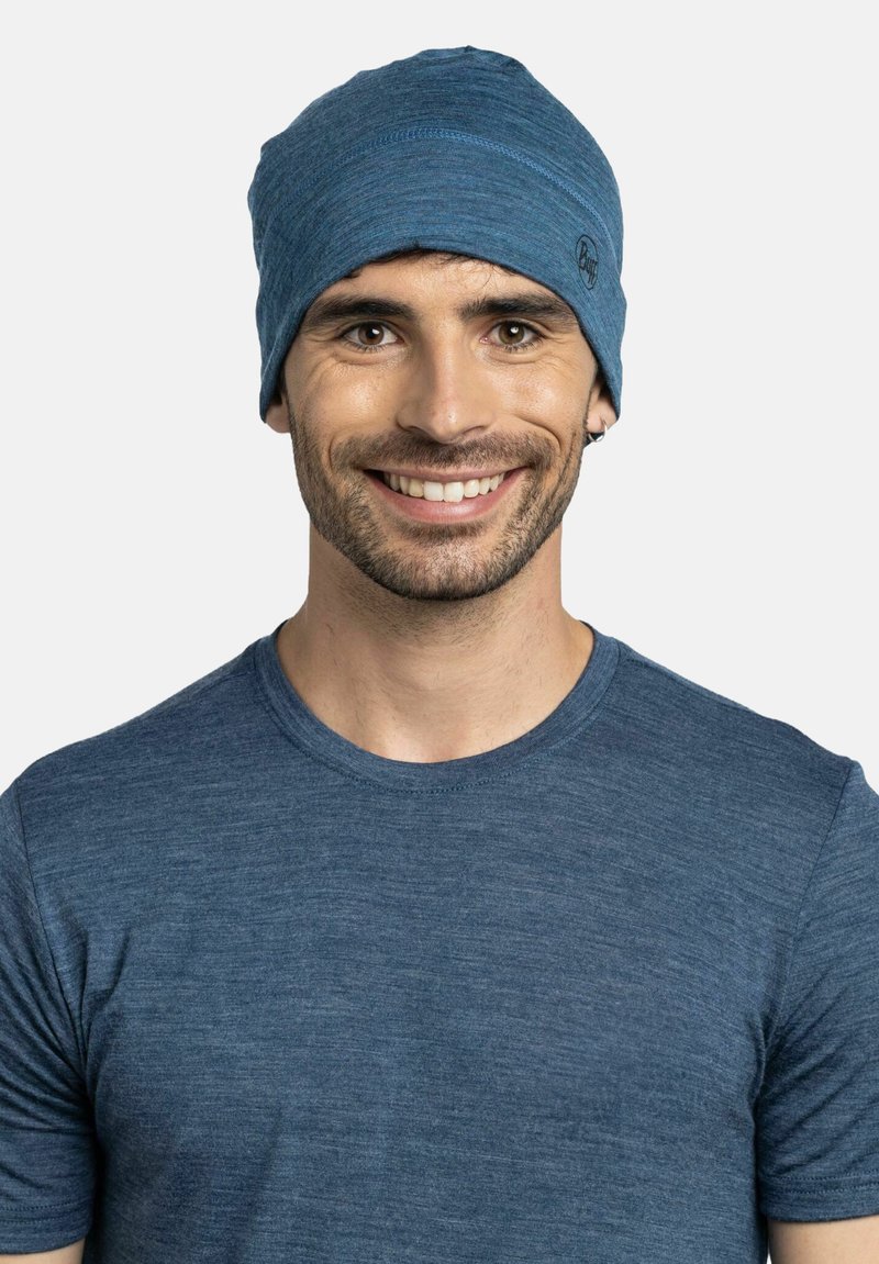 Blue beanie made of soft, textured fabric, featuring a snug fit and subtle stitching details. Worn with a matching blue T-shirt.