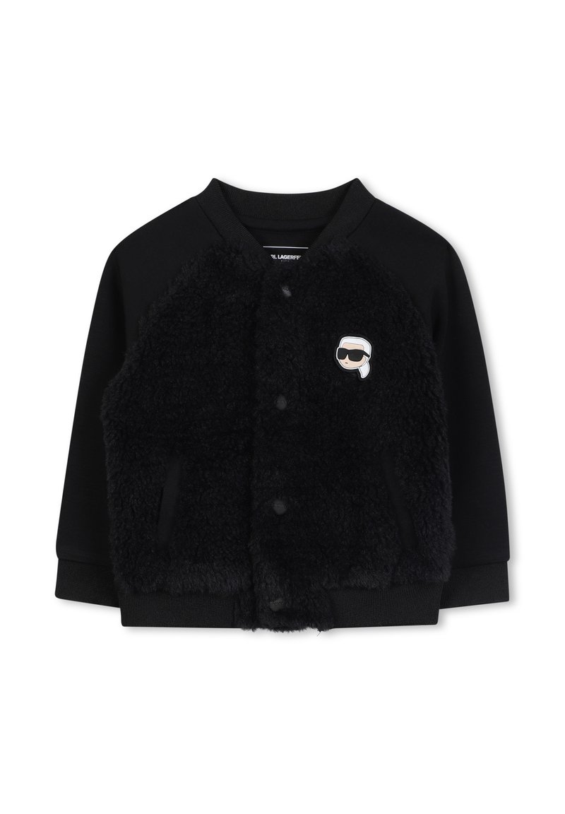 Giubbotto bomber nero con una parte anteriore in pelliccia nera morbida, maniche a maglia e colletto rotondo. Presenta un piccolo logo a cartone animato sul petto sinistro.