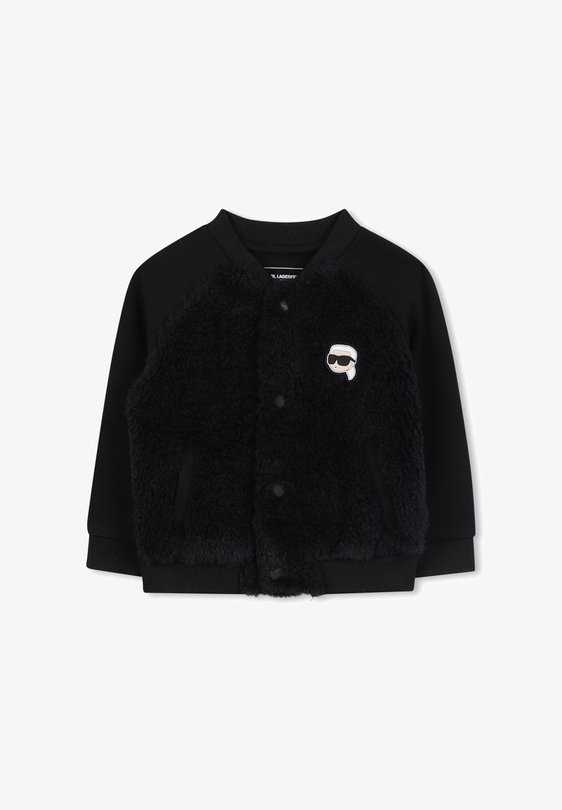 Czarna kurtka bomberka z futrzanym przodem w czarnym kolorze, dzianinowymi rękawami i okrągłym kołnierzem. Posiada małe, kreskówkowe logo na lewej piersi.