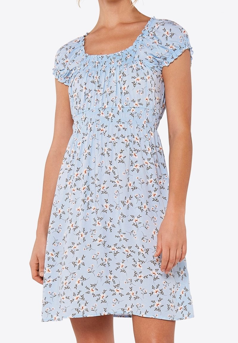 Robe courte bleu clair avec petit imprimé floral, manches bouffantes, encolure froncée et taille cintrée sur une personne debout.