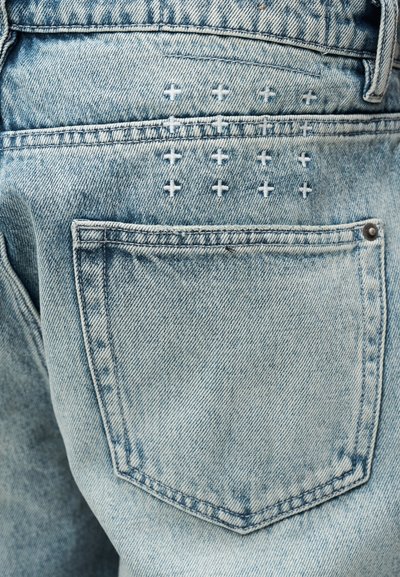 Τζιν ανοιχτού μπλε τζιν με πίσω τσέπη που διαθέτει κεντημένα λευκά σχέδια σταυρού και χαρακτηριστική εξασθένιση.