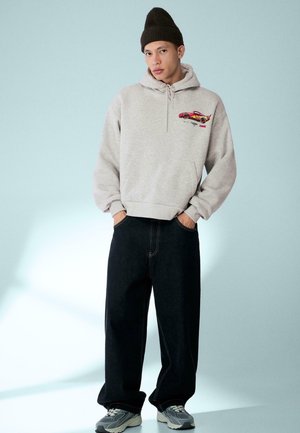 Harmaa huppari, jossa on autokuvio ja säädettävä huppu. Yhdistetty tummansinisiin leveälahkeisiin farkkuihin ja harmaisiin lenkkareihin.