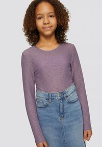 Paarse lange mouwen top met een gestructureerde afwerking, gecombineerd met een hoge taille blauwe spijkerrok. De outfit heeft een ronde halslijn en aansluitende mouwen.