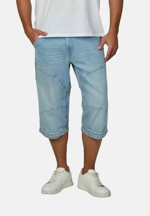 Lichtblauwe denim capri shorts met contrasterende stiksels, schuine zakken en een losse pasvorm. Gecombineerd met witte vetersneakers.