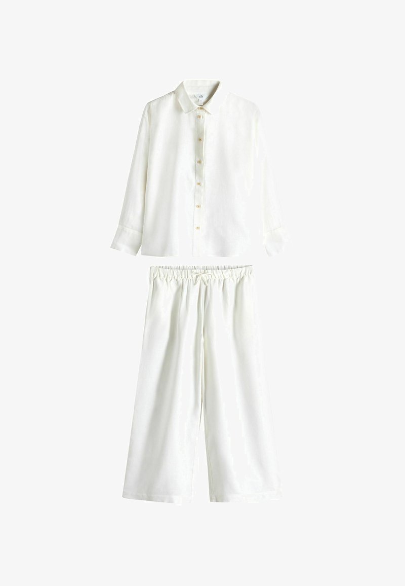 Langärmliges weißes Button-Down-Shirt kombiniert mit lockeren weißen Hosen, die einen elastischen Bund und einen Kordelzug haben.