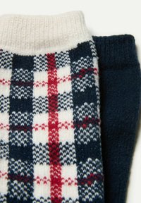 Strikkede sokker med et marineblåt, rødt og hvidt ternet mønster på den ene og en ensfarvet marineblå tekstur på den anden med ribbede manchetter.