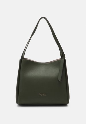 Mørkegrøn skuldertaske i læder med enkelt strop, subtil pebble-textur, bundet detalje på siden og lille gyldent "kate spade new york" logo.