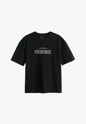 Melna īsām piedurknēm T-krekls ar baltiem dejojošiem tēliem un rozā krāsā centrā krūtīs izvietotu "Keith Haring" parakstu.