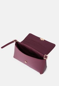 Bordová kabelka s hladkou textúrou, obdĺžnikovým tvarom, magnetickým uzáverom a zhodným popruhom, s jednofarebnou vnútornou podšívkou.