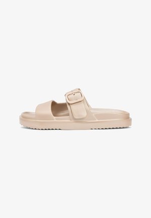 Beige open-toe slide sandaal met dikke zool en grote verstelbare gesp over de voet.