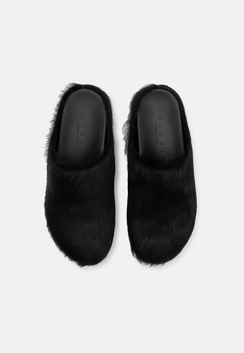 Scarpe slip-on nere in pelliccia con un interno liscio e forma arrotondata, caratterizzate da una parte superiore testurizzata in lungo pelliccia sintetica.