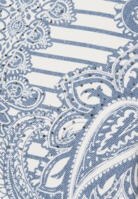 Denim fabric with a paisley pattern in navy blue and white, featuring ornate details and small silver accents throughout the design.