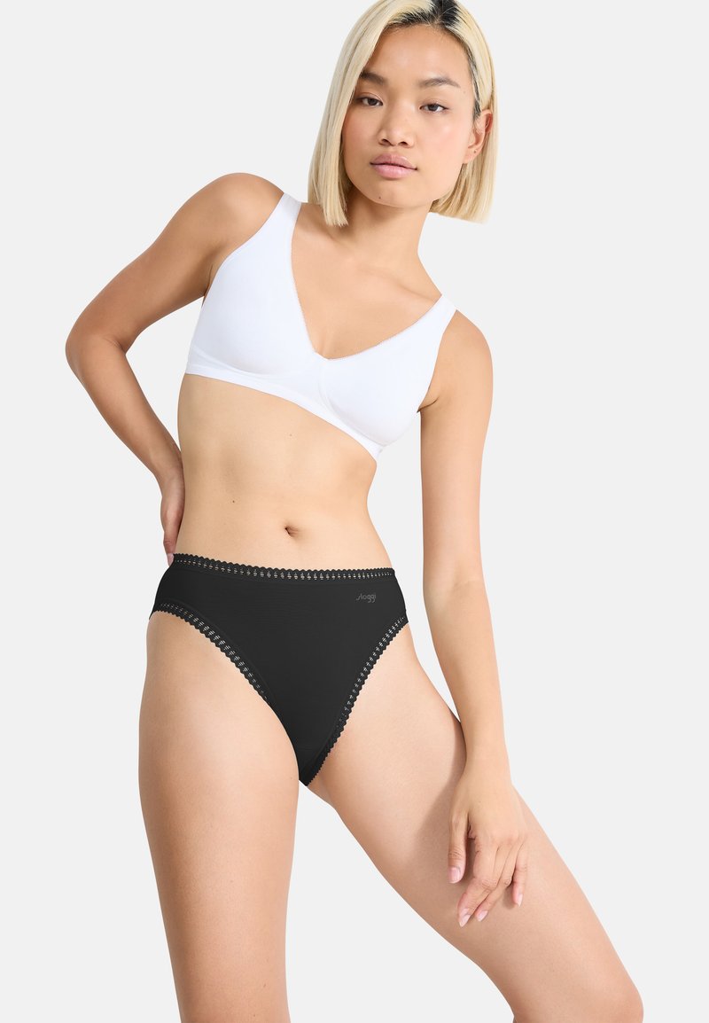 Sort høj talje undertøj med bølget blondetrappe, parret med en hvid pullover-bh. Glat stof, minimalistisk design.