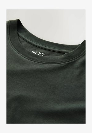 Dunkelgrünes Baumwoll-T-Shirt mit rundem Halsausschnitt und geripptem Saum, versehen mit einem sichtbaren weißen Etikett mit der Aufschrift „NEXT“ im inneren Kragen.