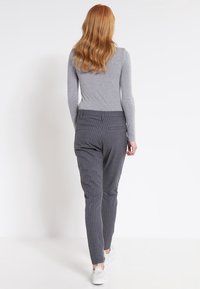 Grijs gestreepte broek met een slim-fit ontwerp, voorzien van een gestructureerde stof, achterzakken en een medium-rise tailleband, gecombineerd met witte schoenen.