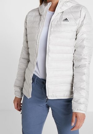 Lichtgrijze pufferjack met capuchon, voorzien van een verticale gestikte afwerking, volledige rits en klein zwart Adidas-logo op de linkerkant van de borst.