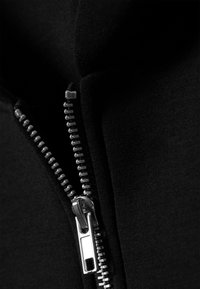 Schwarzer Kapuzenpullover mit silbernem Metallreißverschluss, weicher Stoffstruktur und Nahaufnahme des Reißverschlusses sowie der Stoffdetails.