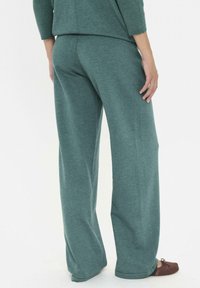 Lässige, ribbelige Sweatpants in Tealfarbe mit einem weiten Bein-Design. Der Stoff wirkt weich und bequem.