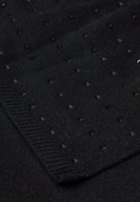 Tissu noir texturé avec de petites découpes carrées et un bord côtelé, présentant un motif uniforme avec des accents réfléchissants tout au long.