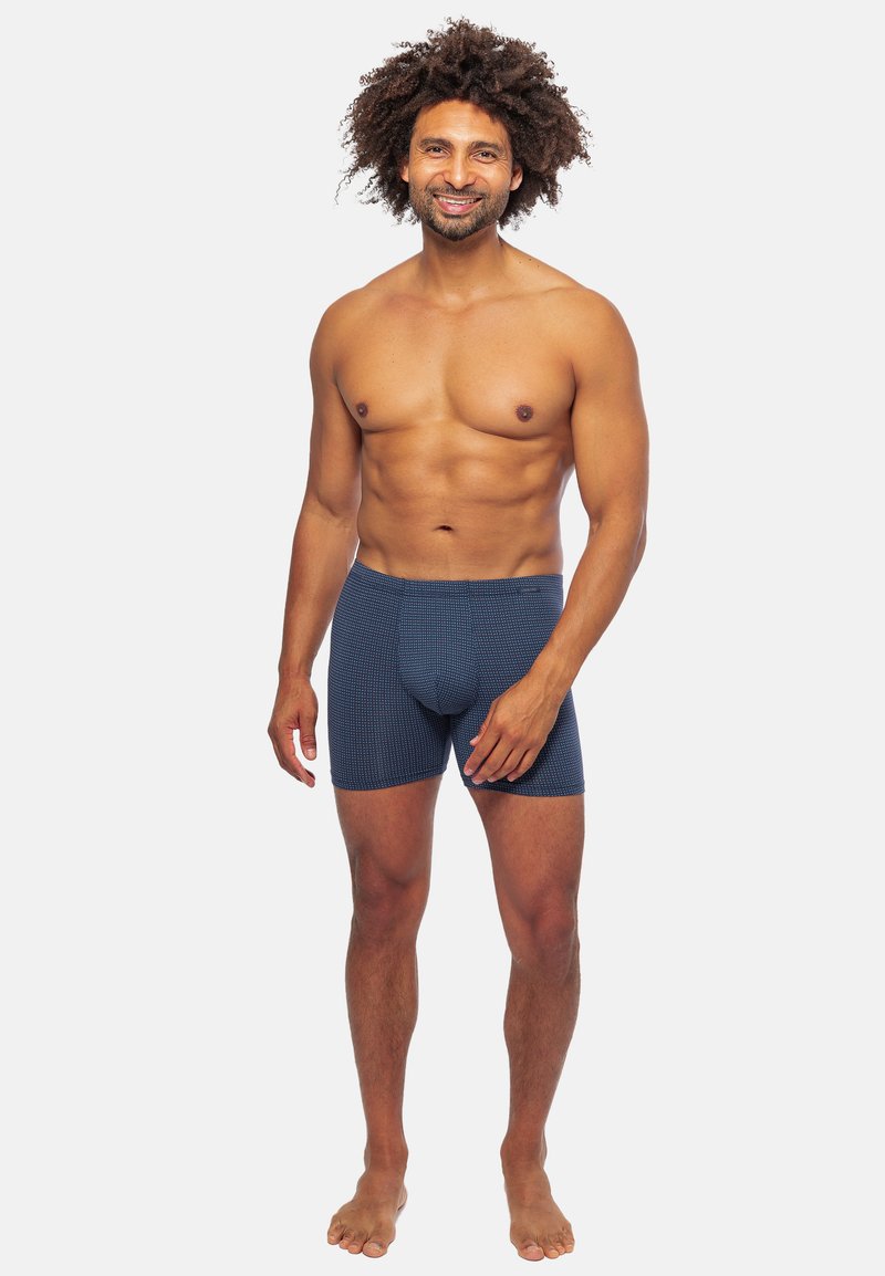 Boxer briefs a fantasia blu con una vestibilità aderente e un elastico in vita, realizzati in un morbido tessuto texturizzato, mostrati su un modello maschile in piedi.