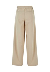 Pantalons larges beige avec une taille élastique, comportant deux poches arrière et une texture lisse. Conception à l'avant plat, sans fermetures visibles.