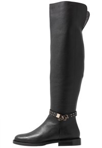 Bota de cuero negra hasta la rodilla con un acabado texturizado, que presenta un acento de hebilla metálica con tachuelas y una suela plana.