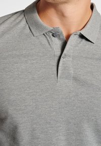 Polo gris con tela texturizada, tapeta de dos botones y cuello clásico. Los botones y las costuras coinciden con el color de la camisa.