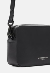 Schwarze Leder-Crossbody-Tasche mit rechteckiger Form, glatter Oberfläche, Reißverschluss und silberfarbenen Beschlägen, mit geprägtem "LIEBESKIND BERLIN".