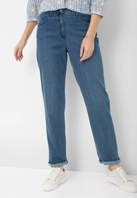 Light blue denim jeans with a relaxed fit, featuring rolled cuffs, five-pocket design, and a smooth texture. Paired with white sneakers.