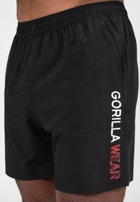 Zwarte sportshorts van zacht materiaal, met een elastische tailleband en het logo "GORILLA WEAR" in wit en rood op de zijkant.