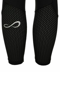 Tubi di compressione neri per polpacci con un motivo a pois bianchi e un simbolo dell'infinito bianco sul braccio sinistro.