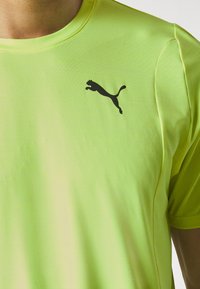 Camiseta atlética de manga corta en un brillante verde neón, hecha de un material ligero, con un logo negro de Puma en el pecho.