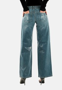 Pantalones vaqueros de mezclilla azul de pierna ancha con acabado desgastado, que cuentan con dos bolsillos traseros y una cintura alta. La tela parece texturizada y duradera.