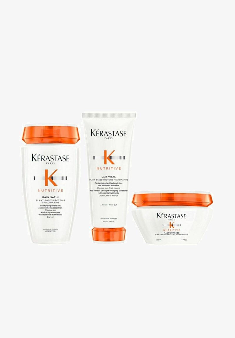 Drei Kérastase-Haarpflegeprodukte mit weißen Behältern und orangefarbenen Akzenten: eine Shampooflasche, eine Conditioner-Tube und eine tiefenwirksame Pflegemaske.