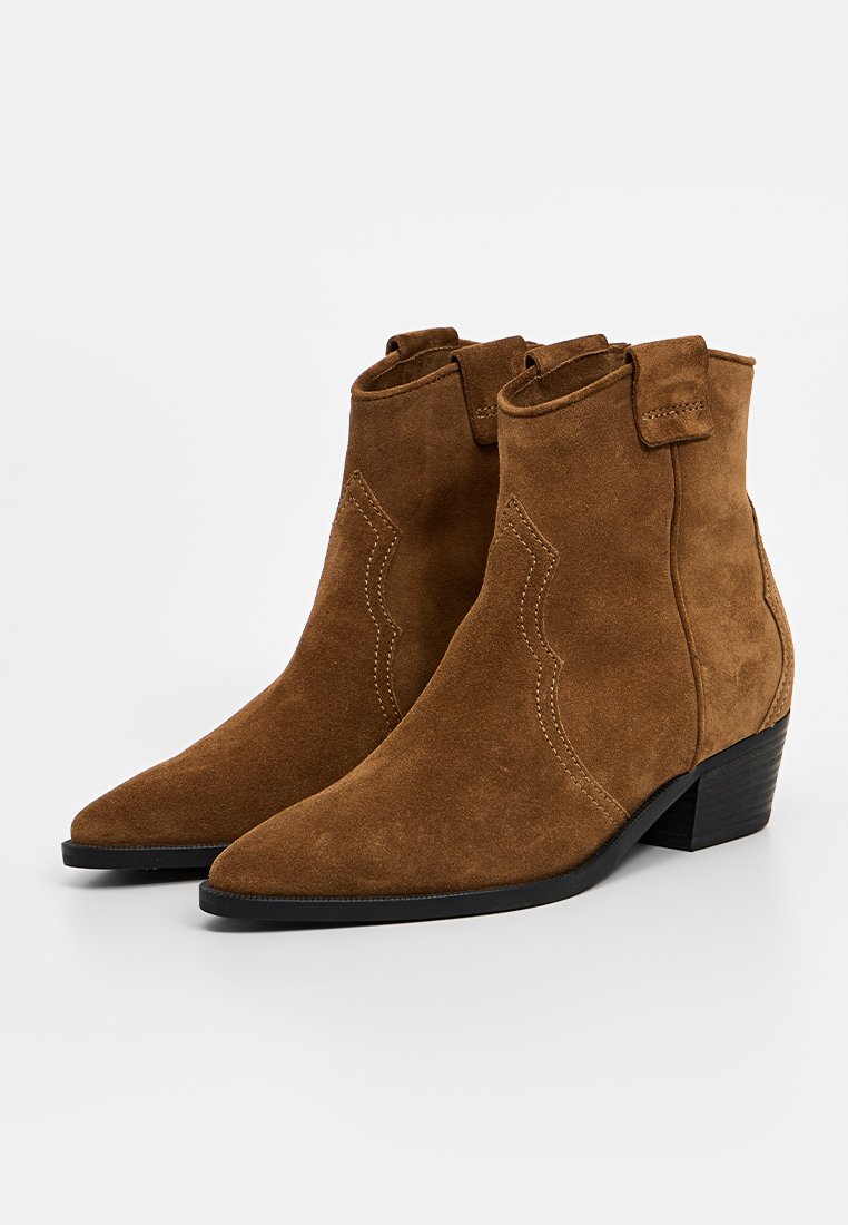 Braune Wildleder-Ankle Boots mit spitzer Zehenpartie, seitlichen Nähdetails und niedrigem Blockabsatz. Mit Zugschlaufen an den oberen Kanten.