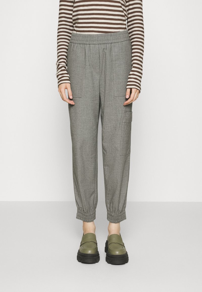 Gray elastic-waist pants with tapered cuffs and side pockets, paired with dark green slip-on shoes, worn over a brown striped long-sleeve top.