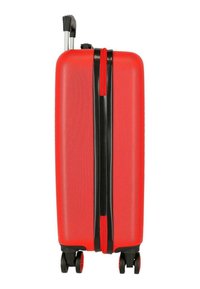 Maleta rígida de color rojo brillante con cuatro ruedas giratorias negras y rojas y asa telescópica extendida, mostrada desde el lateral.