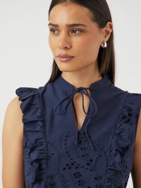 Mørkeblå bluse med flæser på ærmerne og bånd-kravedesign, prydet med broderede blomsterønsker og hulmønsterdetaljer på stoffet.