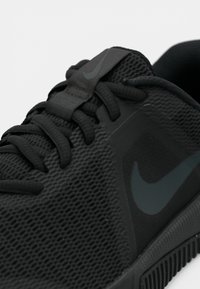 Črni Nike tekaški copati s teksturirano mrežasto zgornjo stranjo, ravnimi vezalkami in toniranim logotipom. Podplat je teksturiran za boljši oprijem.