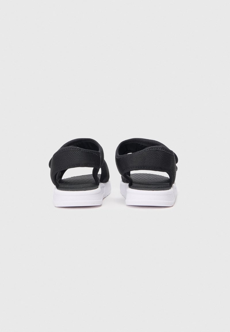 Zwarte sandalen met gestructureerde bandjes, witte zolen en een open achterkant. Heeft verstelbare uitsnijdbandjes voor een veilige pasvorm.