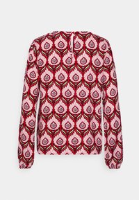 Blusa de manga larga con un patrón floral en rosa y rojo, con cuello redondo y cierre de botones en la parte posterior. Fabricada en tejido suave.