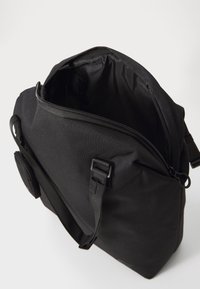 Borsa a tracolla nera realizzata in tessuto resistente; presenta un'apertura con cerniera, tracolla regolabile e tasca esterna. L'interno è foderato.
