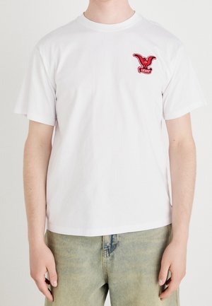 Biała bawełniana koszulka z czerwonym haftowanym logo na lewej piersi, z klasycznym okrągłym dekoltem i krótkimi rękawami.