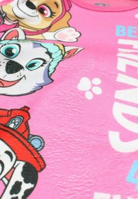 Tissu texturé rose avec des personnages de chiens de dessin animé, y compris un Dalmatien et un husky, affichant des expressions joyeuses et des empreintes de pattes blanches.
