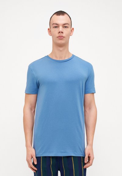 T-shirt bleu à col rond en coton doux. Manches courtes, coupe décontractée, texture lisse et design minimaliste sans motifs.